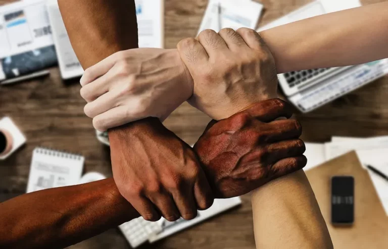 Team members joining hands over a desk